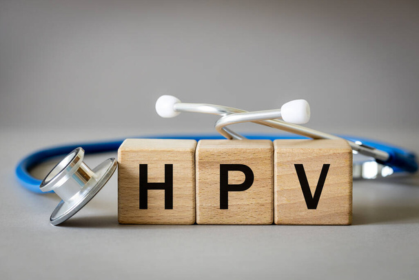 医師は木製のブロック、ヒトパピローマウイルス、医療と健康の概念、医療聴診器と灰色の背景から単語HPVを配置しました - 写真・画像