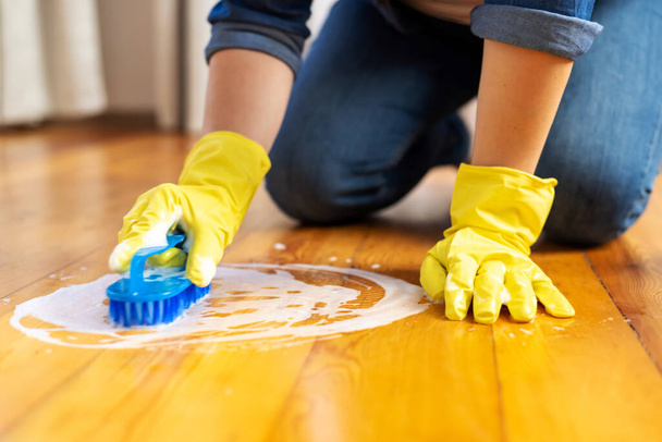 Жінка в гумових рукавичках використовує щітку для чищення підлоги. Концепція домогосподарства та прибирання
. - Фото, зображення