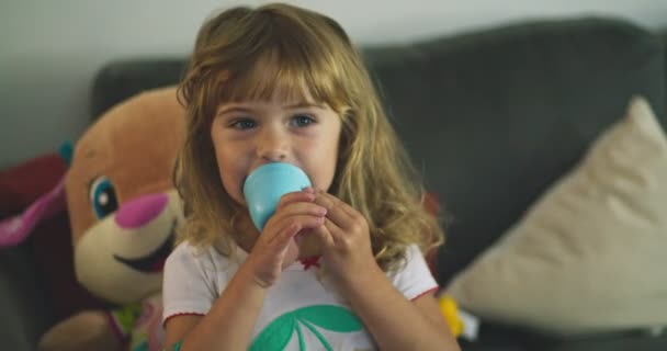Маленька дівчинка вдома грає з чашкою і посміхається
 - Кадри, відео