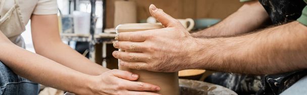 Oříznutý pohled na řemeslníky, kteří vyrábějí hliněnou vázu na keramickém kolečku v keramické dílně, banner - Fotografie, Obrázek