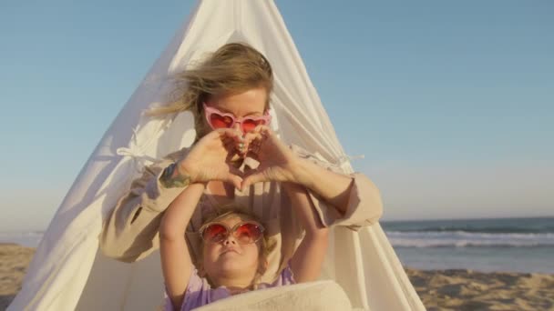 Zbliżenie portrety młodej kobiety i dziewczynki pokazując znak serca, co symbol rękami, poczuć miłość, uśmiech na plaży oceanu. Miłość wsparcie demonstracji, szczęśliwa rodzina razem, dobry związek - Materiał filmowy, wideo