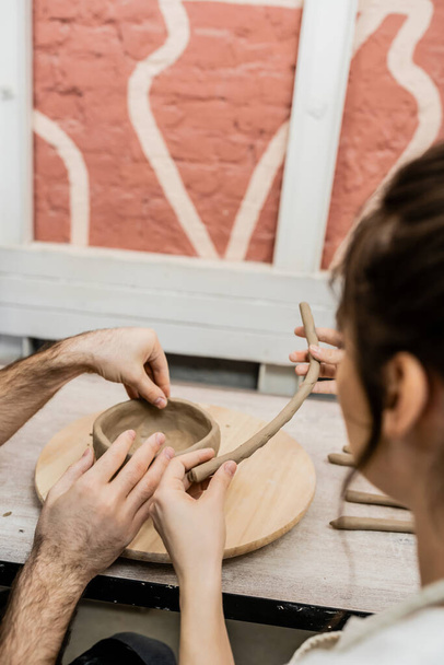 Romantic couple of artisans shaping clay earthenware on wooden board in ceramic studio - Photo, Image