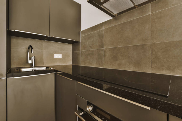 a modern kitchen with black counter tops and white tiles on the wall behind it is a stainless dishwasher - Photo, image