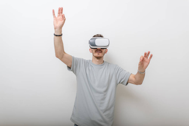 Un homme futuriste portant des lunettes de réalité virtuelle interagit avec l'air dans un fond gris isolé. Photo de haute qualité - Photo, image