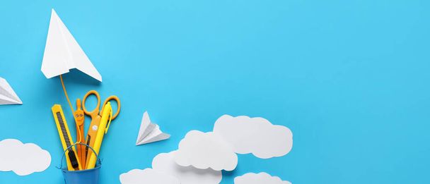 Composition avec avions en papier, nuages et fournitures scolaires sur fond bleu avec espace pour le texte - Photo, image