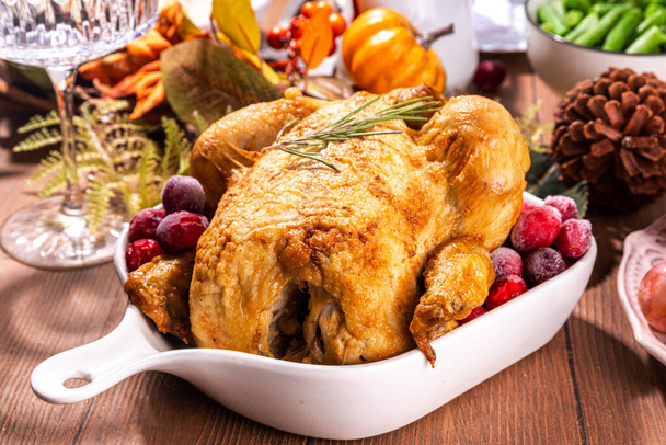 Kiitospäivän perhepäivällinen kattaus lautasilla, ruokailuvälineillä, laseilla, perinteisillä ruokalajeilla paistettu kalkkuna tai kana, kurpitsapiirakka, hedelmät, perunamuusi, vihreät pavut, puinen tausta - Valokuva, kuva