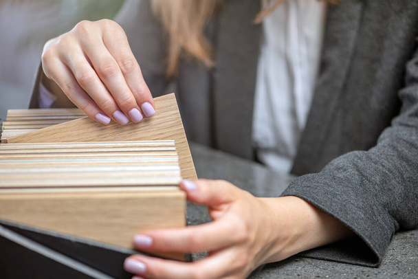 Samples of wood in hands close-up. A woman designer selects wood samples from a collection for a project. High quality photo - Fotografie, Obrázek