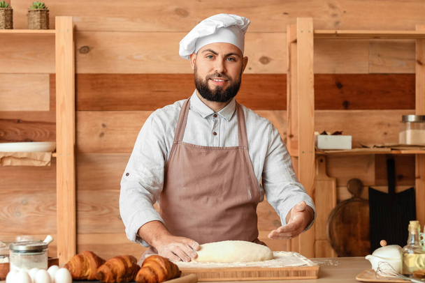 Male baker preparing dough for bread at table in kitchen - Fotografie, Obrázek