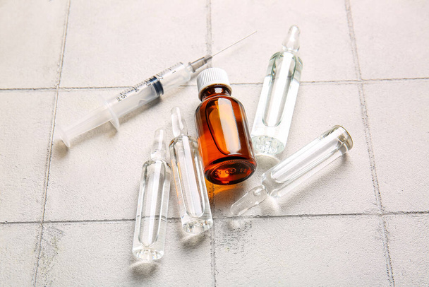 Ampolas médicas com seringa sobre fundo de azulejo branco - Foto, Imagem
