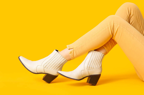 Női lábak stílusos cipőben sárga alapon - Fotó, kép