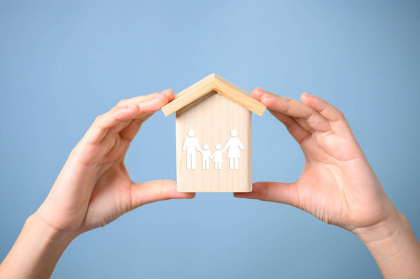 Hands holding wooden house with virtual family, Father mother and children with health care and life insurance, Family protection, Family home lifestyle. High quality photo - Photo, Image