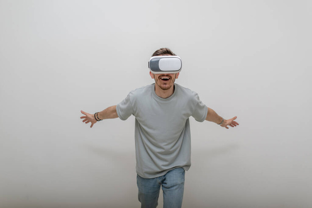 Φουτουριστής που φοράει γυαλιά εικονικής πραγματικότητας αλληλεπιδρά με τον αέρα σε ένα απομονωμένο γκρι φόντο. Υψηλής ποιότητας φωτογραφία - Φωτογραφία, εικόνα