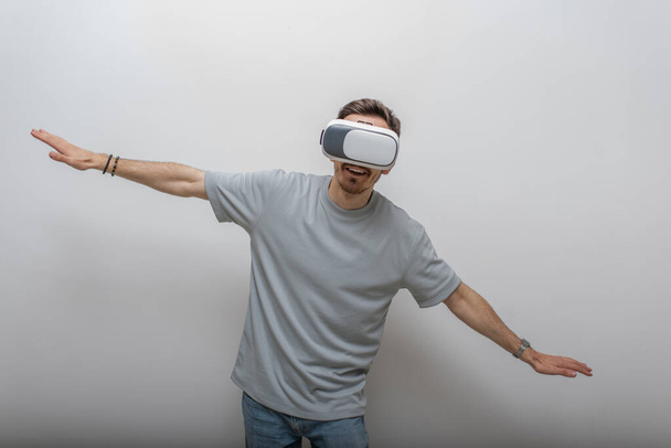 Futuristic man wearing virtual reality glasses interacts with the air in an isolated gray background. High quality photo - Photo, Image
