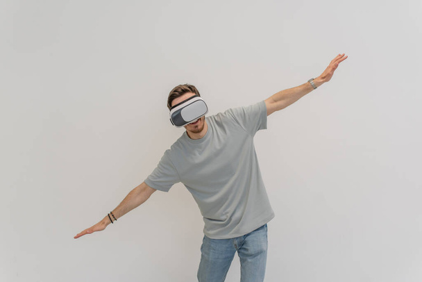 Futuristic man wearing virtual reality glasses interacts with the air in an isolated gray background. High quality photo - Fotografie, Obrázek