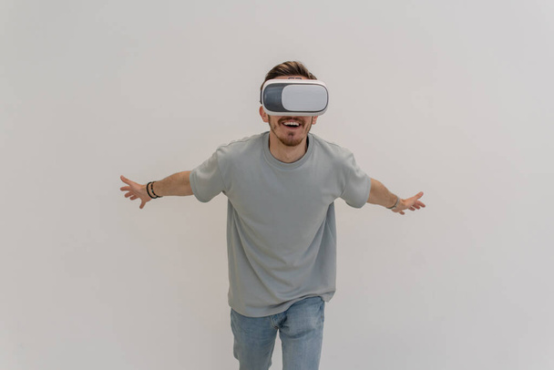 Futuristic man wearing virtual reality glasses interacts with the air in an isolated gray background. High quality photo - Foto, Imagen