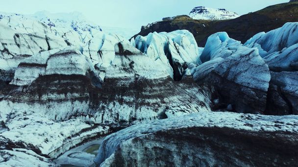 Luftaufnahme der Vatnajokull-Eiskappe in isländischen diamantförmigen Blöcken und Eisbergen mit Spalten. Verschneite Berglandschaft, eisige Felsen, die auf einem zugefrorenen See treiben. Zeitlupe. - Foto, Bild