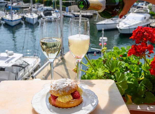 Drinking of French brut champagne sparkling wine with cake Tarte Tropezienne, club party in yacht harbour of Port Grimaud near Saint-Tropez, French Riviera vacation, Var, France - Zdjęcie, obraz
