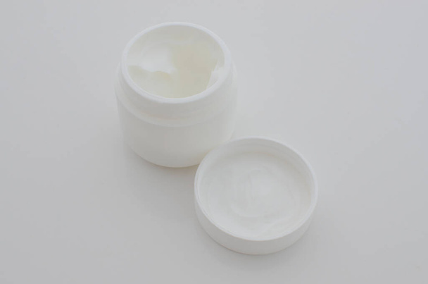 Primer plano de una pequeña olla de crema blanca, que simboliza el cuidado estético y la búsqueda de una piel perfecta. - Foto, Imagen