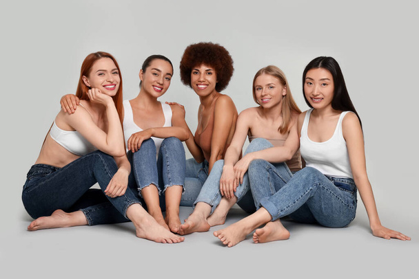 Group of beautiful young women sitting on light grey background - Foto, Imagen