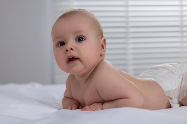 Cute little baby in diaper lying on bed indoors - Foto, Bild