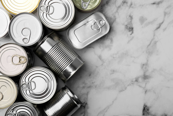 Many closed tin cans on white marble table, flat lay. Space for text - Foto, immagini