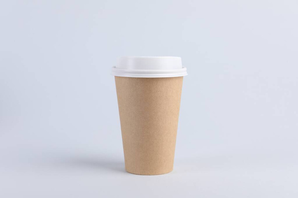 Paper cup with plastic lid on light background. Coffee to go - 写真・画像