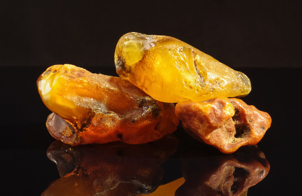Mucchio di pezzi di ambra isolati sulla superficie riflettente nera
 - Foto, immagini