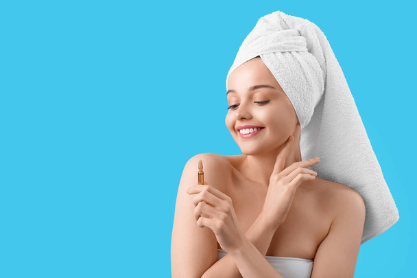 Beautiful young woman with ampule on blue background. Skin care concept - Foto, Imagen