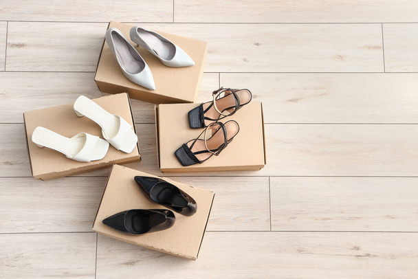 Cajas de cartón con zapatos de tacón sobre fondo de madera claro - Foto, Imagen