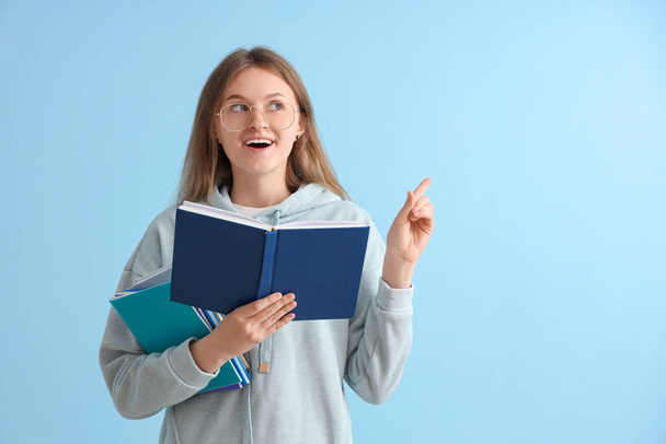 Onnellinen nainen opiskelija eri kirjoja osoittaa jotain sinisellä taustalla - Valokuva, kuva