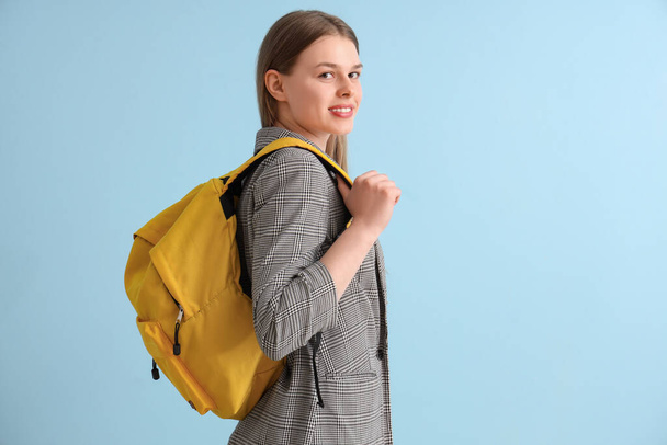 Female student with backpack on blue background - Foto, afbeelding