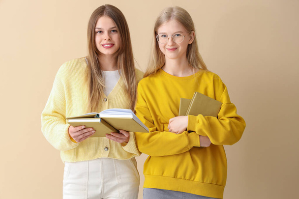 Happy female students books on pale yellow background - Foto, imagen