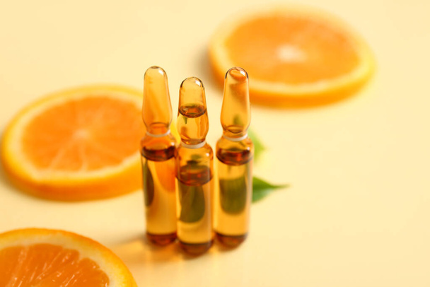 Ампули з вітаміном С і апельсиновими скибочками на бежевому фоні - Фото, зображення