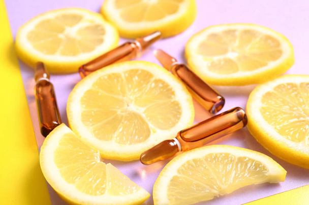 Ампули з вітаміном С і скибочками лимона на барвистому фоні, крупним планом - Фото, зображення