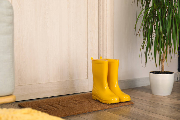 Žluté gumové boty na podložce u dveří - Fotografie, Obrázek