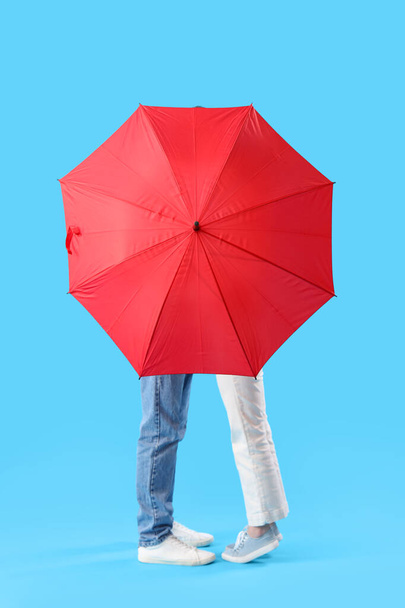 Young couple with umbrella on blue background - Photo, Image