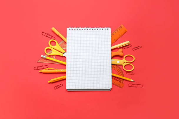 Composition with blank notebook and school stationery on red background - Zdjęcie, obraz