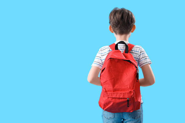 Μικρό αγόρι με σχολική τσάντα σε μπλε φόντο, πίσω όψη - Φωτογραφία, εικόνα