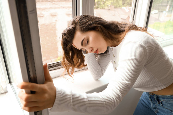 Young woman having panic attack near window - 写真・画像