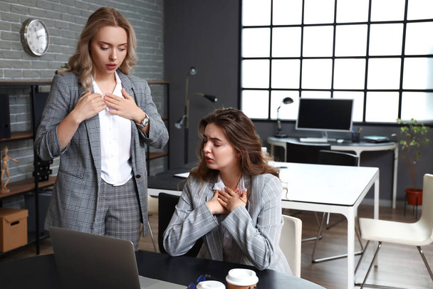 Woman helping her colleague who is having panic attack in office - Foto, Imagen