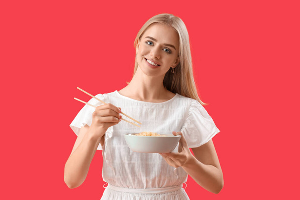 Jovem mulher comendo macarrão no fundo vermelho - Foto, Imagem