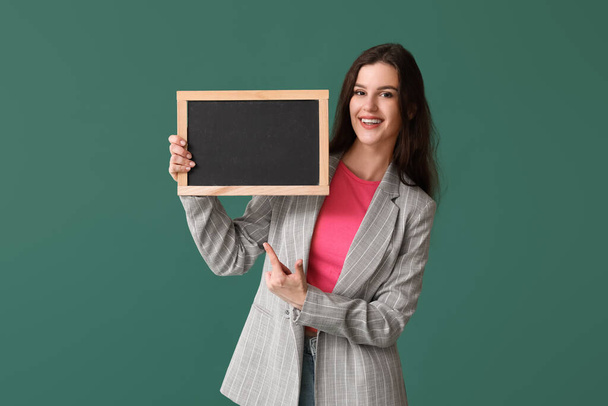 Female teacher pointing at chalkboard on green background - Zdjęcie, obraz