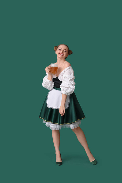 Piękna kelnerka Octoberfest z tańczącym piwem na zielonym tle - Zdjęcie, obraz