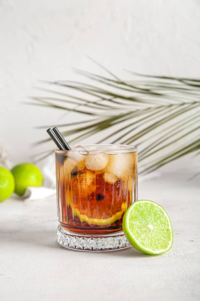 Glass of cold Cuba Libre cocktail and palm leaf on white background - Fotografie, Obrázek