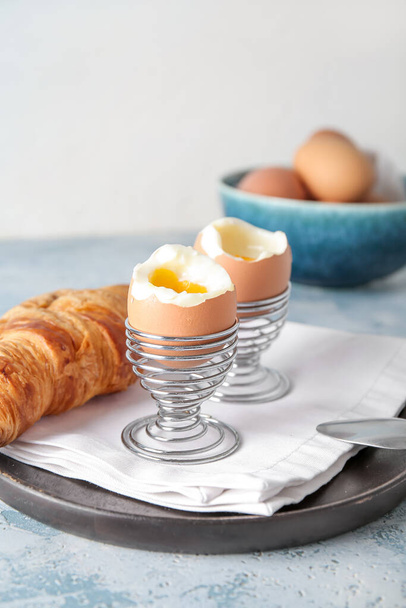 Titulares con huevos de pollo cocidos y croissant sobre mesa azul - Foto, imagen