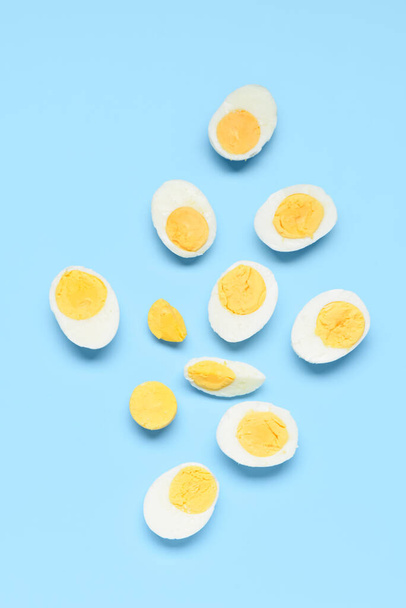 Hälften von leckeren gekochten Eiern mit Scheibe auf blauem Hintergrund - Foto, Bild