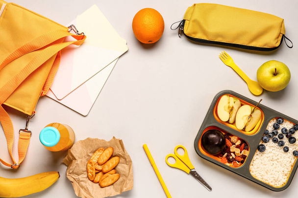 Hátizsák, írószer és uzsonnás doboz ízletes ételekkel szürke alapon - Fotó, kép