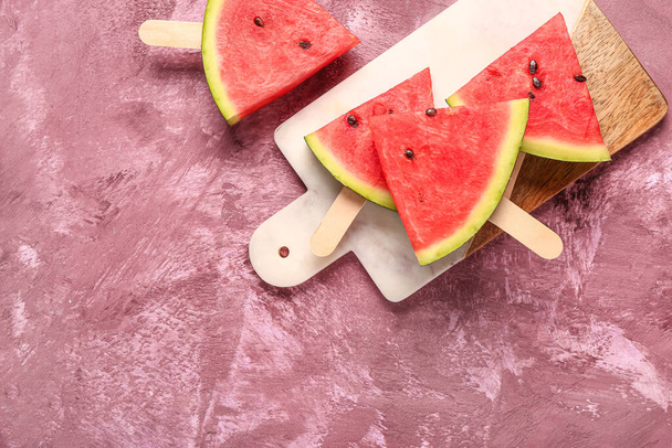 Board with sweet watermelon sticks on purple background - 写真・画像