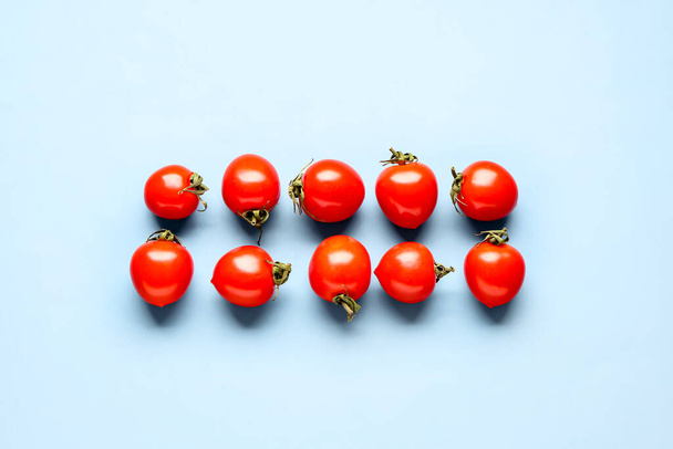Many fresh cherry tomatoes on blue background - Valokuva, kuva