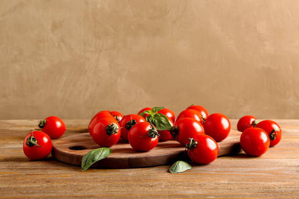 Deska s čerstvými cherry rajčaty a bazalkou na dřevěném stole - Fotografie, Obrázek